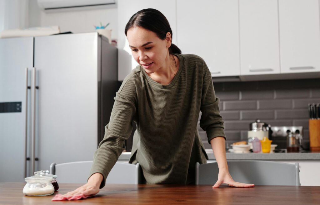 pexels photo 6224257 6224257 Woman cleaning a kitchen table with a cloth in a modern kitchen setting, maintaining hygiene.